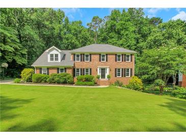 Traditional two-story brick home featuring a well-manicured lawn and mature landscaping at 1135 Parkview Sw Way, Lilburn, GA 30047