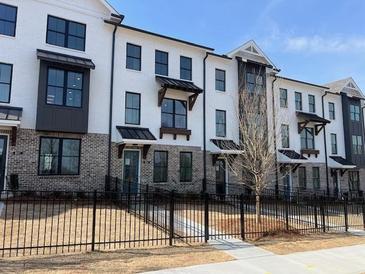 New townhome exteriors featuring classic brick and white painted facade with black trim and gated front yards at 633 Silva St # 133, Cumming, GA 30040
