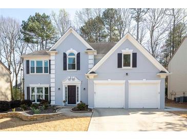 Charming two-story home featuring a two-car garage, well-manicured lawn, and classic architectural details at 10715 Glenbarr Dr, Johns Creek, GA 30097