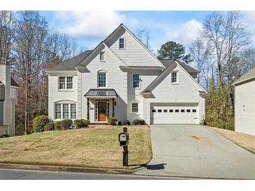 Beautiful two-story white brick home with a manicured lawn and a two-car garage on a sunny day at 2130 Waters Ferry Dr, Lawrenceville, GA 30043
