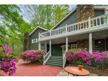 Charming home entrance with brick path, stone chimney and stairs leading to a covered porch with vibrant azaleas at 2977 Glover Dr, Cumming, GA 30040