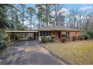 Charming single-story home with a brick facade, complemented by a covered parking area and mature trees at 4222 Webb Rd, Tucker, GA 30084