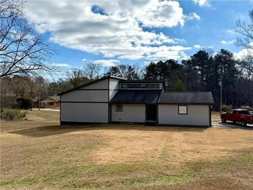 Side view of grey two-story home showcasing unique architecture and a large yard at 1902 Mack Rd, Douglasville, GA 30135