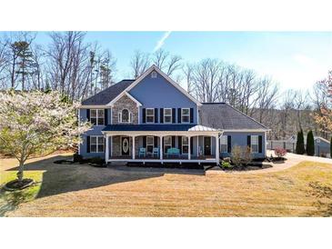 Charming two-story home with a rocking chair front porch, a manicured lawn, and mature trees at 114 Hardwood Ln, Canton, GA 30115