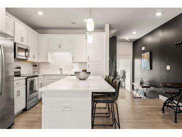 Modern kitchen featuring white cabinets, stainless steel appliances, and a large island with counter seating at 2030 Main Nw St # 207, Atlanta, GA 30318