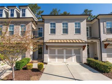 Charming brick townhome featuring a two-car garage and meticulously landscaped front yard at 5018 Towneship Creek Rd, Roswell, GA 30075
