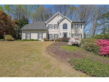 Charming two-story home with black shutters and beautifully landscaped front yard and blooming azaleas at 1201 Lake Washington Dr, Lawrenceville, GA 30043