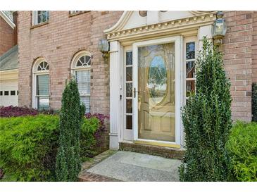 Charming brick home entrance with decorative glass door, sidelights, arched windows, and manicured landscaping at 6317 Southland Forest Dr, Stone Mountain, GA 30087