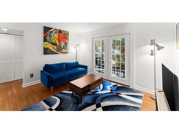 Bright living room featuring a blue sofa, hardwood floors, and french doors to the outside at 1355 Euclid Ne Ave # 21B, Atlanta, GA 30307