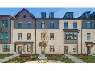 View of townhomes with neutral brick, black trim, and meticulously maintained landscaping offering an inviting curb appeal at 608 Marimba Pike, Mcdonough, GA 30253