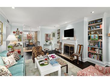 Bright living room featuring a fireplace, built-in bookshelves, and seamless access to the dining area at 2260 Peachtree Nw Rd # D6, Atlanta, GA 30309