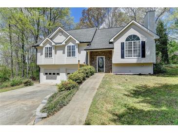 Charming home featuring a two-car garage and stone-accented entryway for added curb appeal at 7040 Shady Oak Ln, Cumming, GA 30040