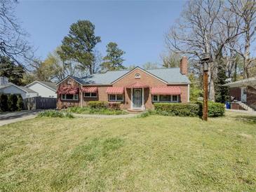 Charming brick home featuring a well-manicured lawn, mature trees, and red awnings at 1368 Scott Blvd, Decatur, GA 30030