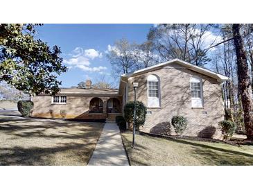 Charming brick home featuring a well-manicured lawn and walkway leading to a covered front porch at 3868 Prentiss Dr, Decatur, GA 30034