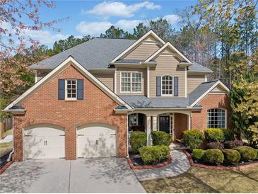Beautiful brick and tan home featuring a two-car garage, well-manicured landscaping, and a charming covered front porch at 548 Lawton Bridge Sw Rd, Smyrna, GA 30082