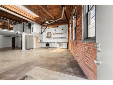 Bright open living area with exposed brick, loft, and modern kitchen details under a wood ceiling at 644 Wells Sw St # 8, Atlanta, GA 30310