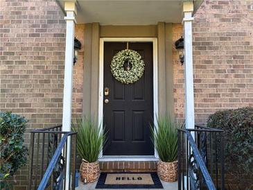 Charming brick home featuring a black front door adorned with a welcoming wreath and potted plants at 6980 Roswell Rd # E1, Atlanta, GA 30328