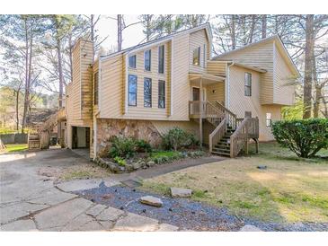View of the two-story home with wood and stone and a wooden stair walkway up to the front door at 752 Alison Jane Ne Ct, Kennesaw, GA 30144