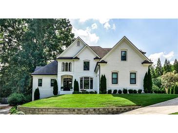 Elegant, two-story white brick home with manicured lawn and mature trees, exuding curb appeal and classic charm at 237 Webney Se Dr, Marietta, GA 30068