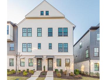 Charming three-story townhome featuring a white facade, brick accents, and a well-maintained lawn at 6569 Beacon Dr, Sandy Springs, GA 30328