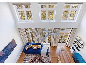 Bright living room featuring high ceilings, large windows, and a stylish blue sofa with a decorative rug at 1221 Caroline Ne St # 201, Atlanta, GA 30307