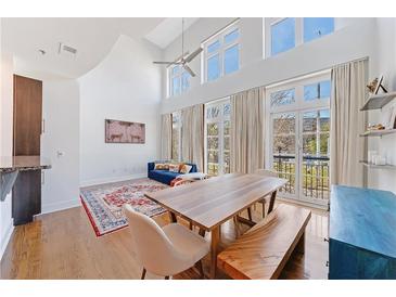 Bright living room features tall windows, hardwood floors, and a spacious dining area with custom table at 1221 Caroline Ne St # 201, Atlanta, GA 30307
