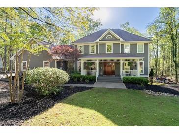 Charming two-story home featuring a welcoming front porch with wood columns and neatly landscaped yard with mature trees at 608 Apache Trl, Woodstock, GA 30189