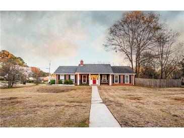 Charming brick home featuring a red front door, black shutters and inviting front porch at 3874 Carriage Sw Ln, Conyers, GA 30094