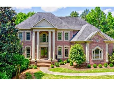 Grand brick home featuring stately columns, arched windows, mature trees, and lush landscaping at 2698 Bonar Hall Path, Duluth, GA 30097