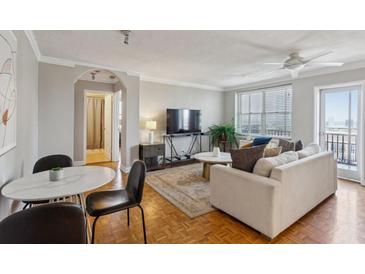 Comfortable living room with hardwood floors, neutral walls, ceiling fan, balcony access, and dining area at 300 Peachtree Ne St # 19B, Atlanta, GA 30308