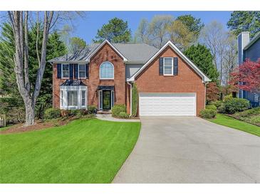 Charming two-story brick home with a well-manicured lawn, mature trees and a two car garage at 1673 Chadwick Ridge Dr, Lawrenceville, GA 30043