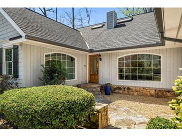 Charming home entrance featuring a stone walkway, tidy landscaping and a wood front door with glass panels at 570 Glen Eagles Se Cir, Marietta, GA 30067