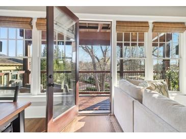 Bright living room featuring hardwood floors, neutral walls, and access to a deck with wooded views at 5910 Bond St # 401, Cumming, GA 30040