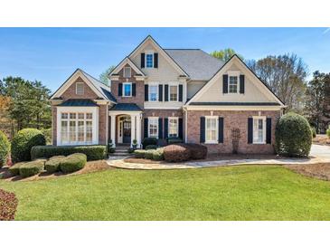 Beautiful brick home featuring manicured lawn, mature trees, and architectural design elements at 305 Inman Pl, Roswell, GA 30075