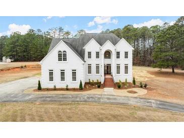 Stunning white brick two-story home with striking architectural details and a meticulously maintained lawn at 636 Ginger Cake Rd, Fayetteville, GA 30214