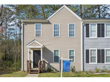 Two-story home with beige siding, black door, covered porch, and manicured lawn at 7004 Panda Ln, Austell, GA 30168