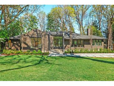 Charming home boasts a manicured lawn, lush landscaping, and a striking modern design with large windows at 1718 Barnesdale Ne Way, Atlanta, GA 30309