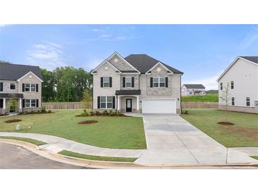 Charming two-story home with a gray brick facade, lush lawn, and a two-car garage at 989 Blue Juniper Cir, Loganville, GA 30052