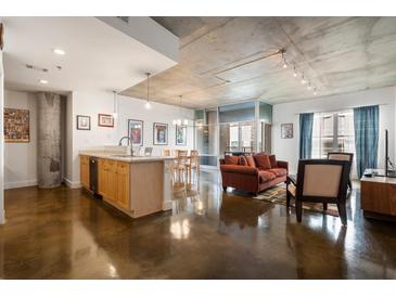 Bright living room with modern kitchen, concrete ceiling, and large windows to let in natural light at 845 Spring St # 125, Atlanta, GA 30308