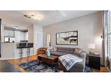 Modern living room featuring a gray sofa, hardwood floors, and neutral decor with an open view to the kitchen at 10 Perimeter Summit Ne Blvd # 1204, Brookhaven, GA 30319