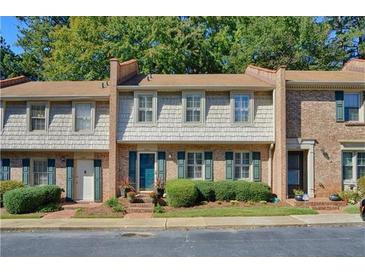 Charming townhome featuring manicured landscaping, a brick facade, and a welcoming teal door at 3403 Ashwood Ln, Atlanta, GA 30341