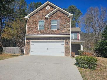 Two-story home with a stone facade, attached garage and driveway on a sunny day at 100 Iverson Pl, Temple, GA 30179