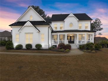 Elegant white home with a welcoming front porch and manicured landscaping at 6635 Canyon Cv, Cumming, GA 30028
