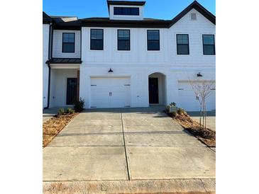 Charming townhome featuring a white brick facade, black-trimmed windows, and convenient two-car garages at 36 S Auburn Landing Pl, Auburn, GA 30011