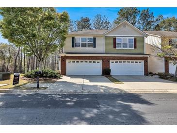 Two-story townhome with a two-car garage, brick accents, and a well-maintained front yard under a blue sky at 1080 Treymont Ln, Lawrenceville, GA 30045