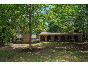 Charming brick home featuring an arched front porch and a lush, green, tree-filled front yard at 2544 Peyton Woods Sw Trl, Atlanta, GA 30311