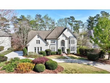 Beautiful two-story home with a well-manicured lawn, mature trees, and circular driveway at 1562 Asheforde Dr, Marietta, GA 30068