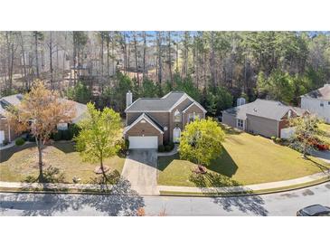 Well-maintained brick home with mature trees, manicured lawn and attached two-car garage in suburban neighborhood at 3940 Medlock Park Dr, Snellville, GA 30039