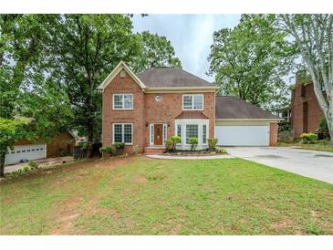 Charming two-story brick home with mature trees and a well-manicured lawn on a cloudy day at 5611 Manassas Run, Stone Mountain, GA 30087