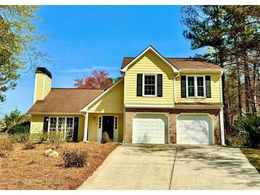 Inviting two-story yellow home with a well-maintained front yard and two-car garage at 4722 Bradford Ln, Powder Springs, GA 30127